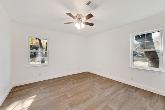 empty room with light wood-type flooring, plenty of natural light, visible vents, and baseboards