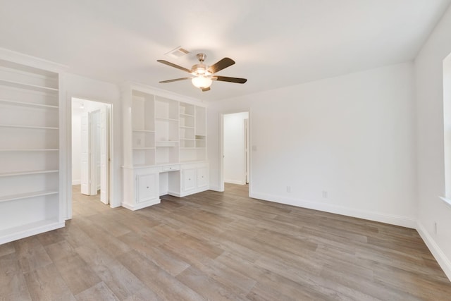 unfurnished living room with ceiling fan, light hardwood / wood-style floors, built in desk, and built in features