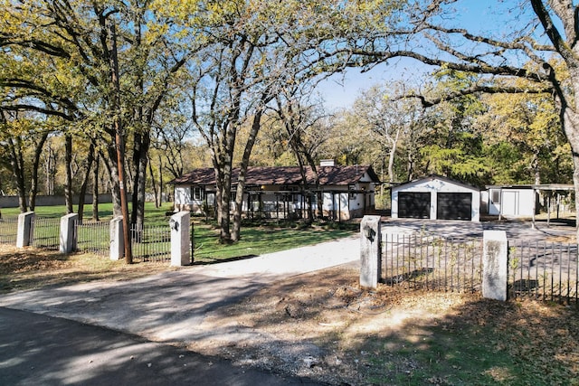 exterior space with a fenced front yard, a detached garage, and an outbuilding