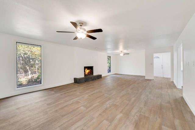 unfurnished living room featuring ceiling fan, a large fireplace, and light hardwood / wood-style flooring