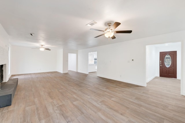 unfurnished living room with a brick fireplace, light hardwood / wood-style flooring, and ceiling fan