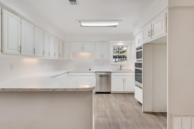 kitchen featuring white cabinets, sink, light wood-type flooring, kitchen peninsula, and stainless steel appliances