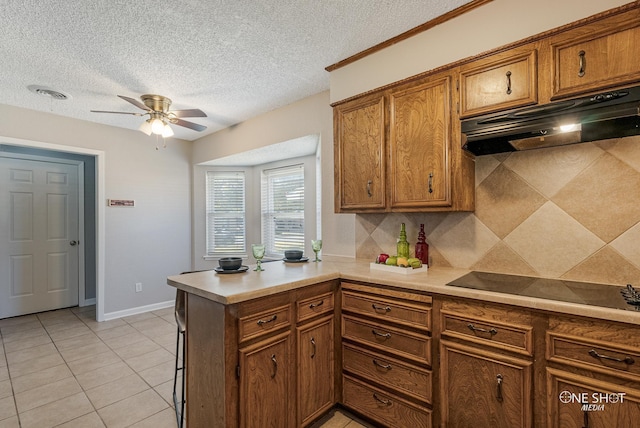 kitchen featuring kitchen peninsula, backsplash, a textured ceiling, black electric cooktop, and light tile patterned floors