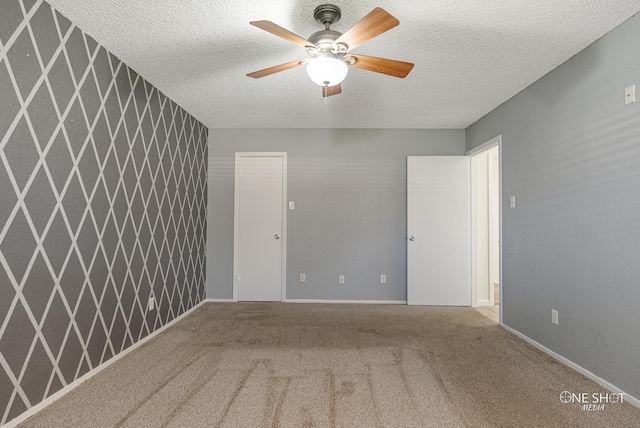 unfurnished room featuring carpet, ceiling fan, and a textured ceiling