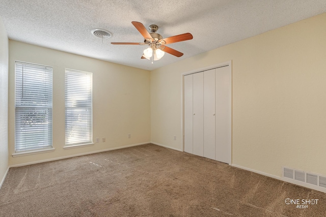 unfurnished bedroom featuring ceiling fan, carpet floors, and a textured ceiling