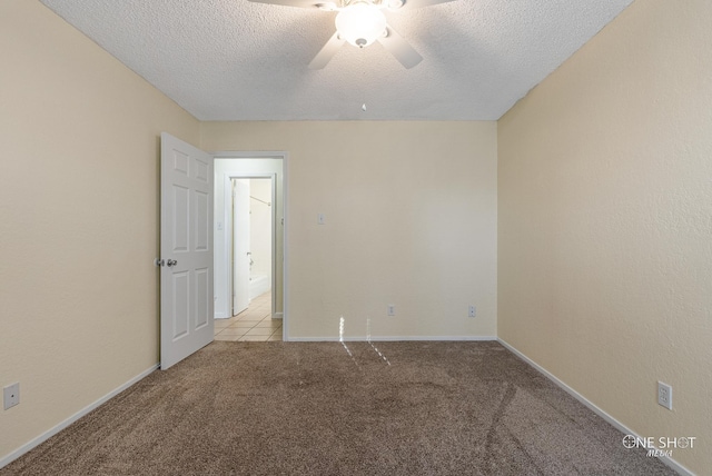 carpeted empty room with ceiling fan and a textured ceiling