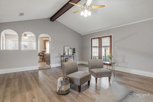 sitting room with lofted ceiling with beams, ceiling fan, light hardwood / wood-style floors, and a textured ceiling