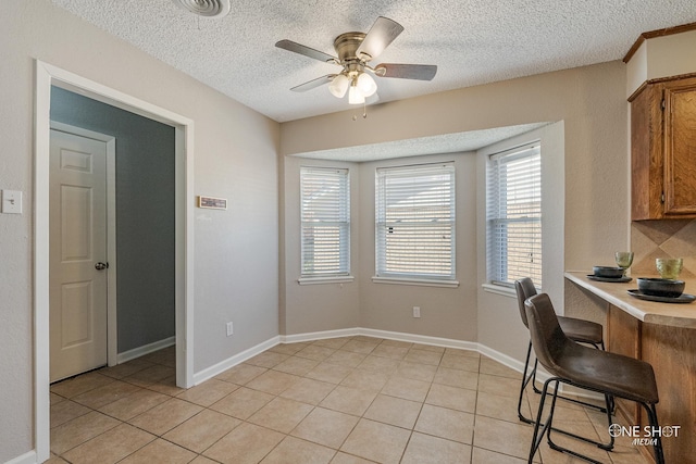 tiled office space with a textured ceiling and ceiling fan