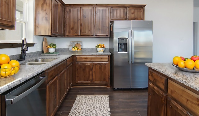 kitchen featuring light stone counters, sink, stainless steel appliances, and dark wood-type flooring