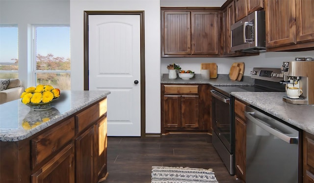 kitchen featuring light stone countertops, appliances with stainless steel finishes, dark hardwood / wood-style flooring, and dark brown cabinetry