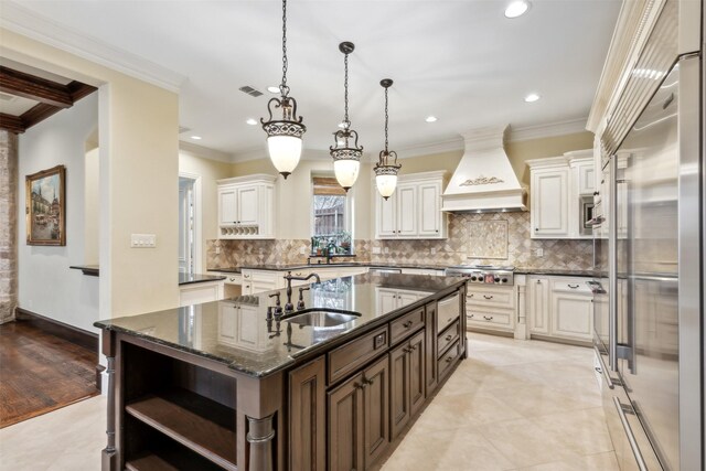 kitchen with custom range hood, built in appliances, crown molding, and sink