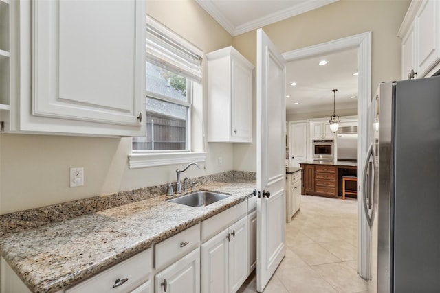 kitchen with light stone countertops, appliances with stainless steel finishes, sink, white cabinetry, and hanging light fixtures