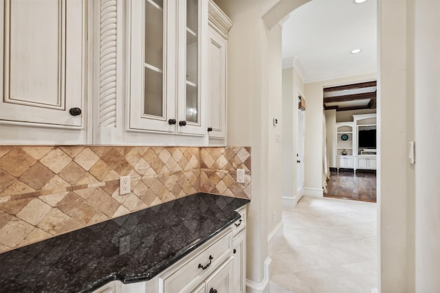 kitchen featuring backsplash, dark stone countertops, light hardwood / wood-style flooring, and ornamental molding