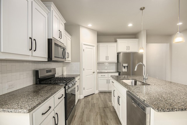 kitchen with sink, stainless steel appliances, light hardwood / wood-style flooring, pendant lighting, and white cabinets