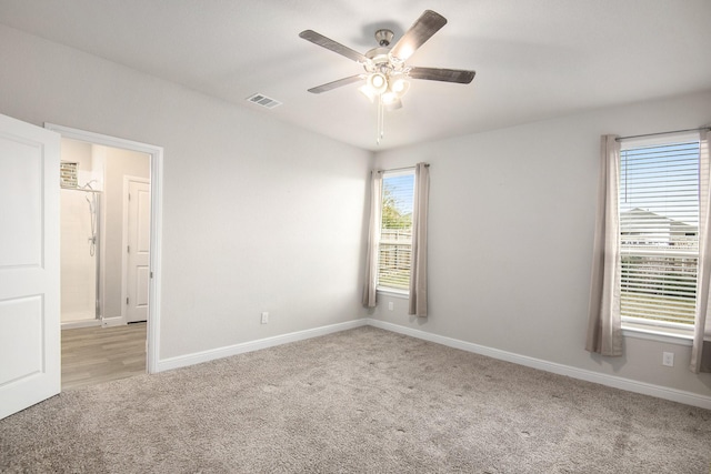 carpeted empty room with a wealth of natural light and ceiling fan