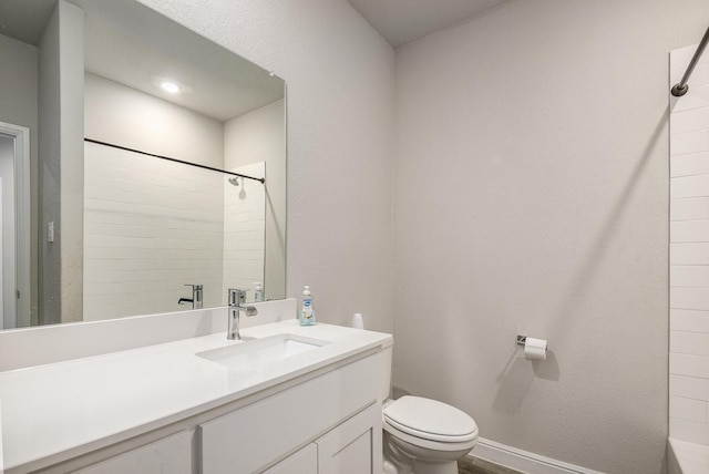 bathroom with a tile shower, vanity, and toilet