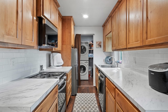 kitchen featuring sink, dark hardwood / wood-style floors, stacked washing maching and dryer, tasteful backsplash, and stainless steel appliances