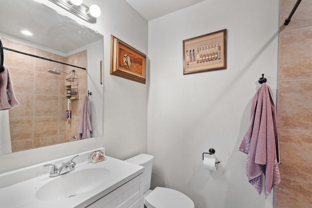 bathroom with a tile shower, vanity, and toilet