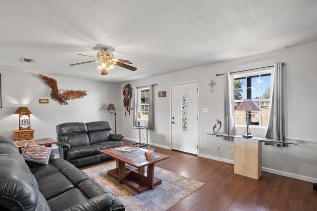 living room with ceiling fan, dark wood-type flooring, and a textured ceiling