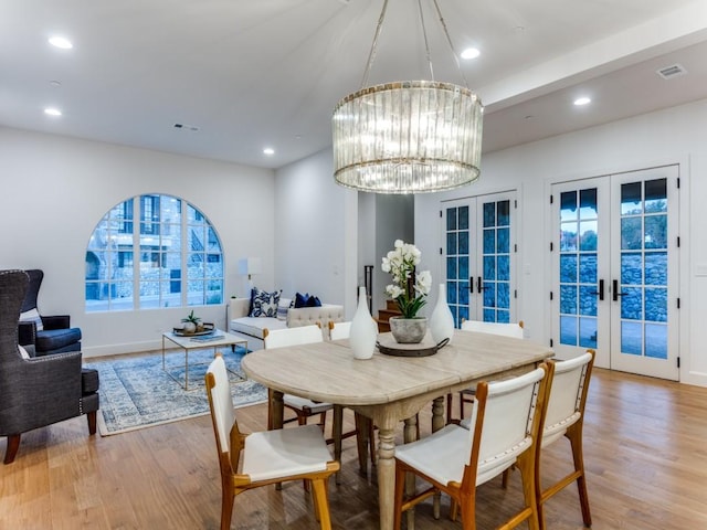 dining area with a notable chandelier, light hardwood / wood-style floors, and french doors