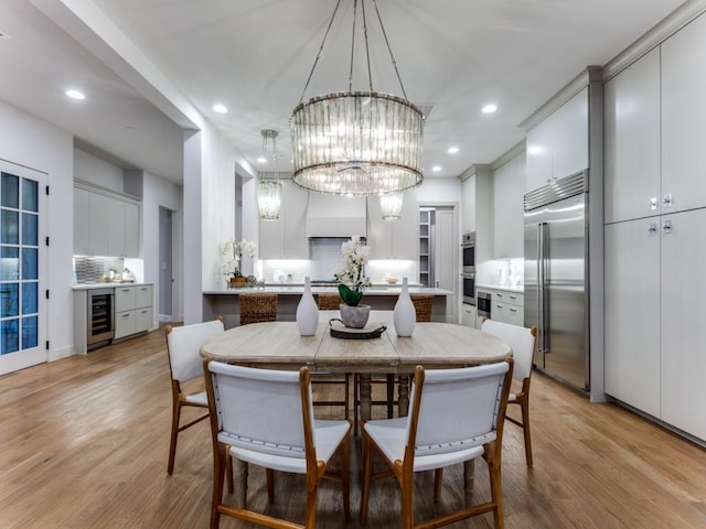 dining area featuring beverage cooler, a notable chandelier, and light wood-type flooring