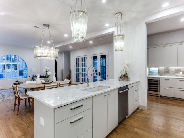 kitchen featuring pendant lighting, sink, beverage cooler, and light hardwood / wood-style flooring