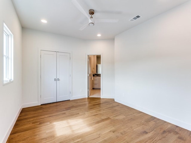 unfurnished bedroom featuring light wood-type flooring, a closet, ceiling fan, and ensuite bathroom