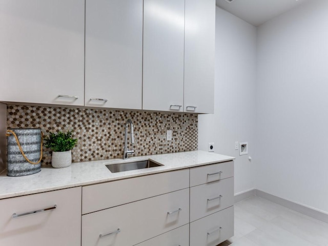 kitchen featuring light stone countertops, tasteful backsplash, and sink