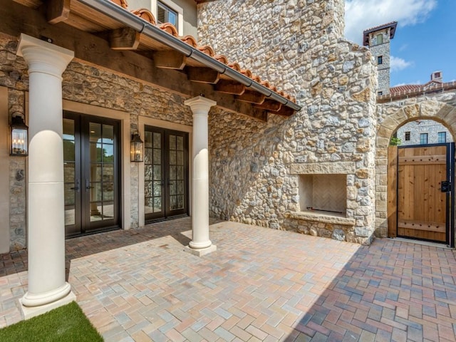 view of patio / terrace with french doors and an outdoor stone fireplace