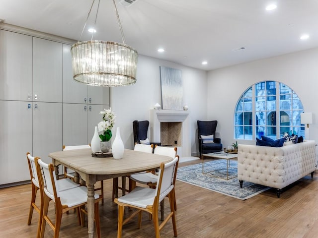 dining space with light wood-type flooring and an inviting chandelier