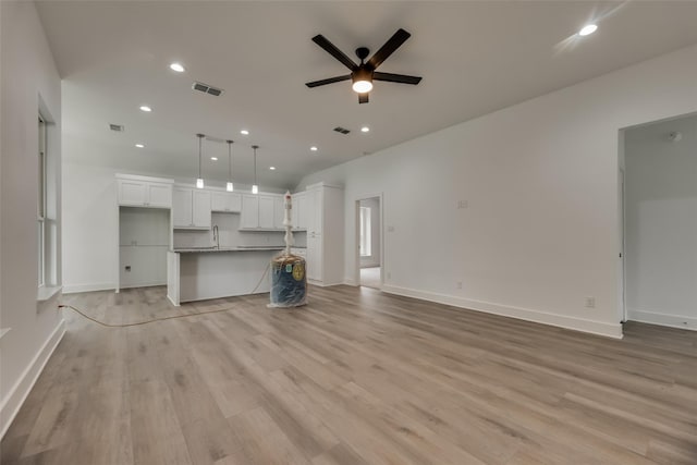 unfurnished living room with ceiling fan, light hardwood / wood-style floors, and sink