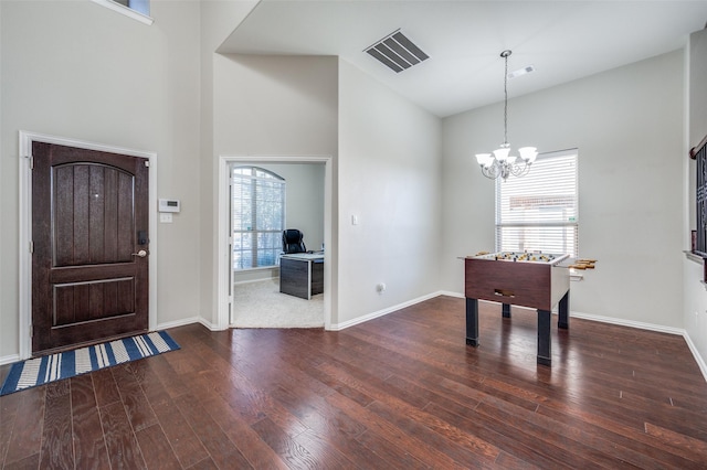 foyer entrance featuring a towering ceiling, dark hardwood / wood-style floors, and a notable chandelier