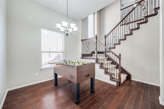 playroom featuring dark hardwood / wood-style floors, a notable chandelier, and a towering ceiling