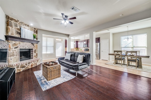 living room with a fireplace, hardwood / wood-style floors, and ceiling fan with notable chandelier