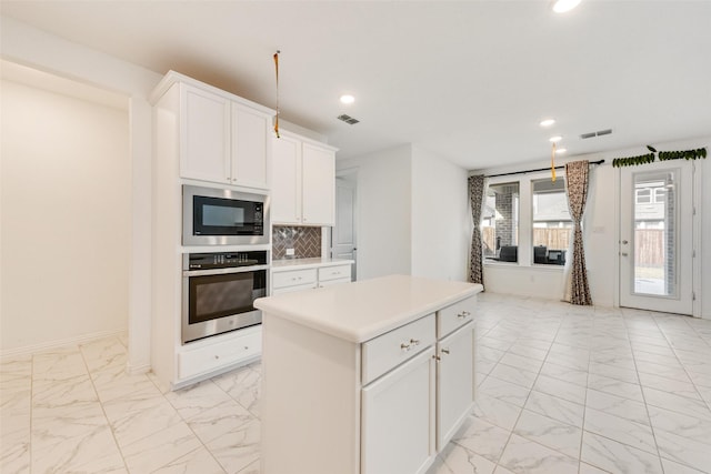 kitchen with marble finish floor, a kitchen island, light countertops, and oven