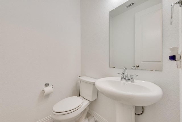 bathroom featuring toilet, a sink, visible vents, and baseboards