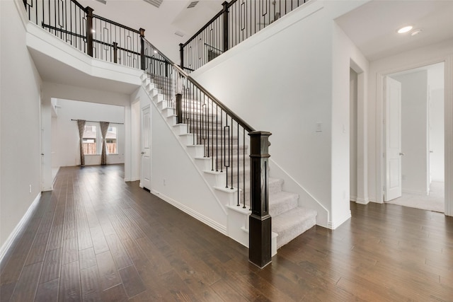 stairs featuring a high ceiling, baseboards, wood finished floors, and recessed lighting