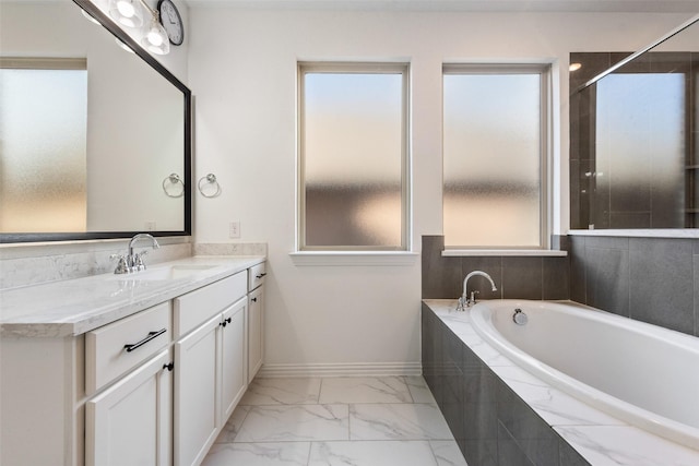 bathroom with marble finish floor, vanity, baseboards, and a bath