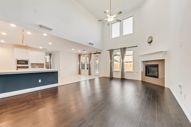 unfurnished living room featuring a ceiling fan, recessed lighting, a fireplace, and wood finished floors