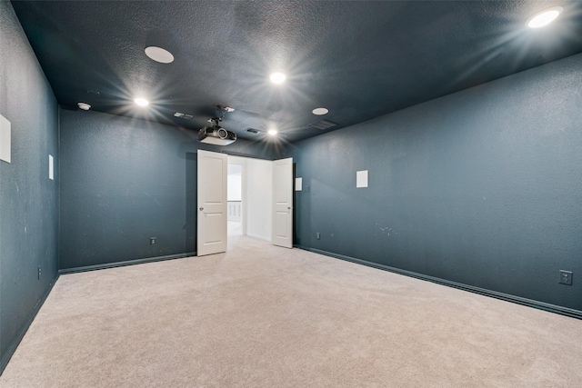 cinema featuring a textured ceiling, a textured wall, visible vents, and light colored carpet