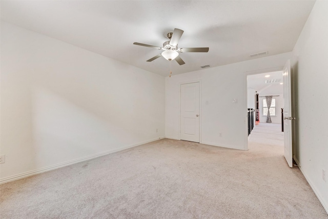 empty room with a ceiling fan, light carpet, visible vents, and baseboards