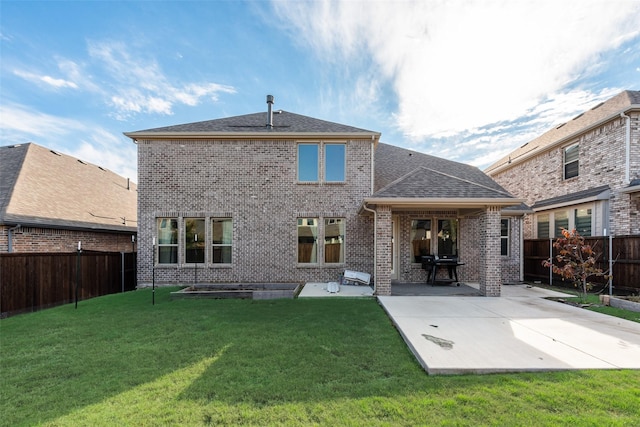 back of property with a fenced backyard, brick siding, roof with shingles, a lawn, and a patio area