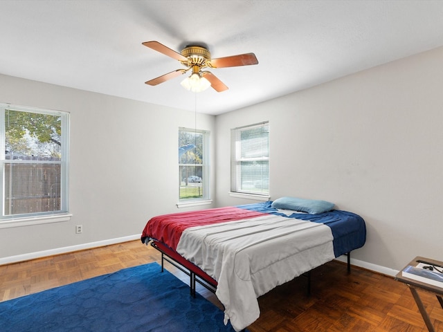 bedroom featuring multiple windows, dark parquet flooring, and ceiling fan