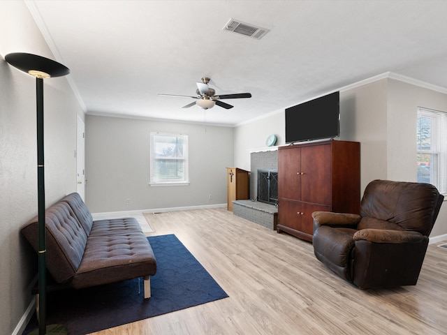 sitting room with a healthy amount of sunlight, light hardwood / wood-style floors, crown molding, and a brick fireplace