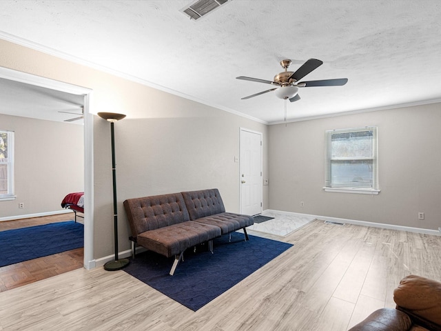 living area featuring light wood-type flooring, a wealth of natural light, crown molding, and ceiling fan