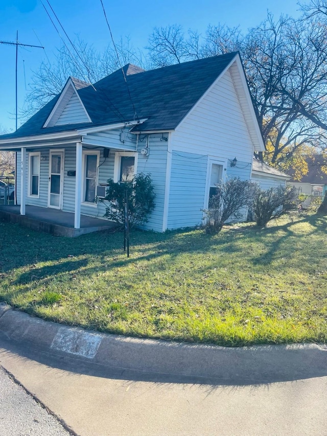 view of side of property with covered porch and a yard