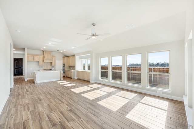 unfurnished living room with vaulted ceiling, light wood-type flooring, and ceiling fan