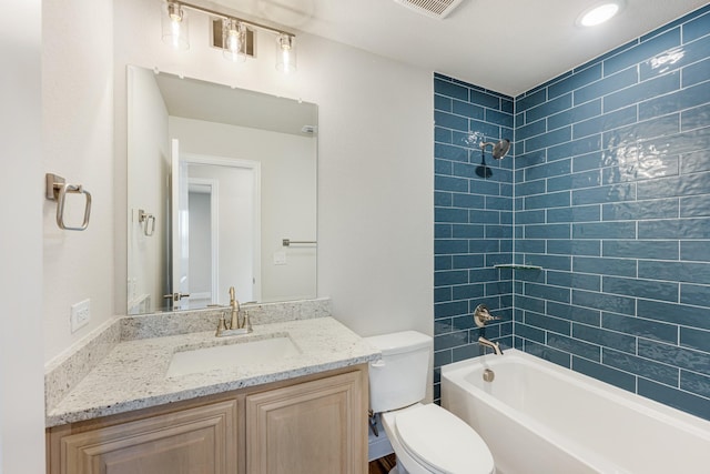 full bathroom featuring vanity, tiled shower / bath combo, and toilet