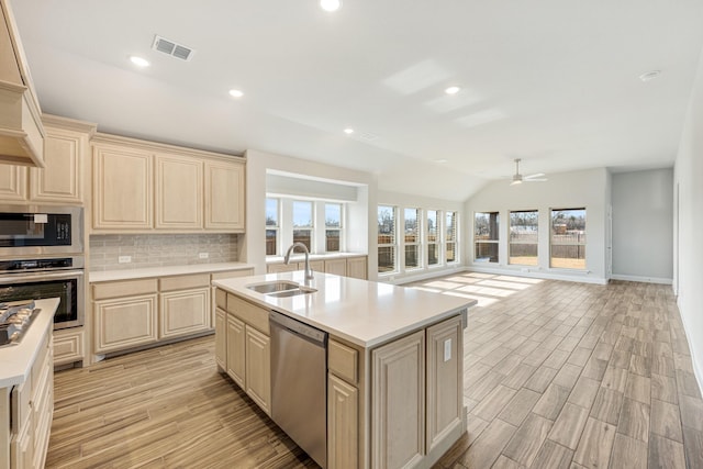 kitchen with stainless steel appliances, a center island with sink, lofted ceiling, ceiling fan, and sink