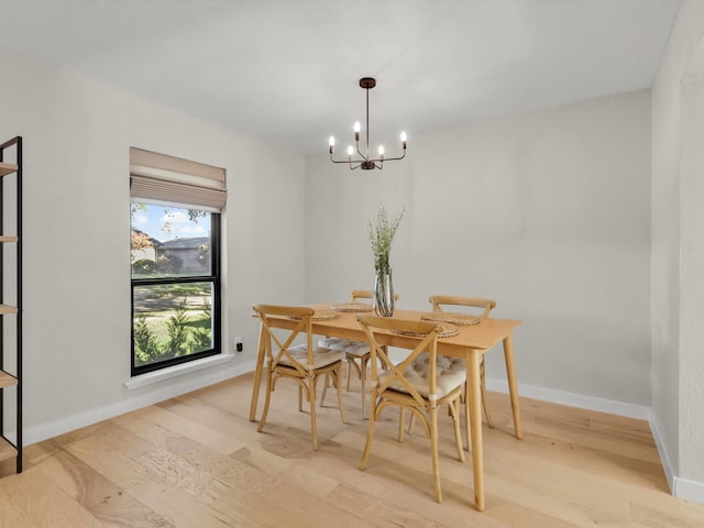 dining space with light hardwood / wood-style floors and a chandelier